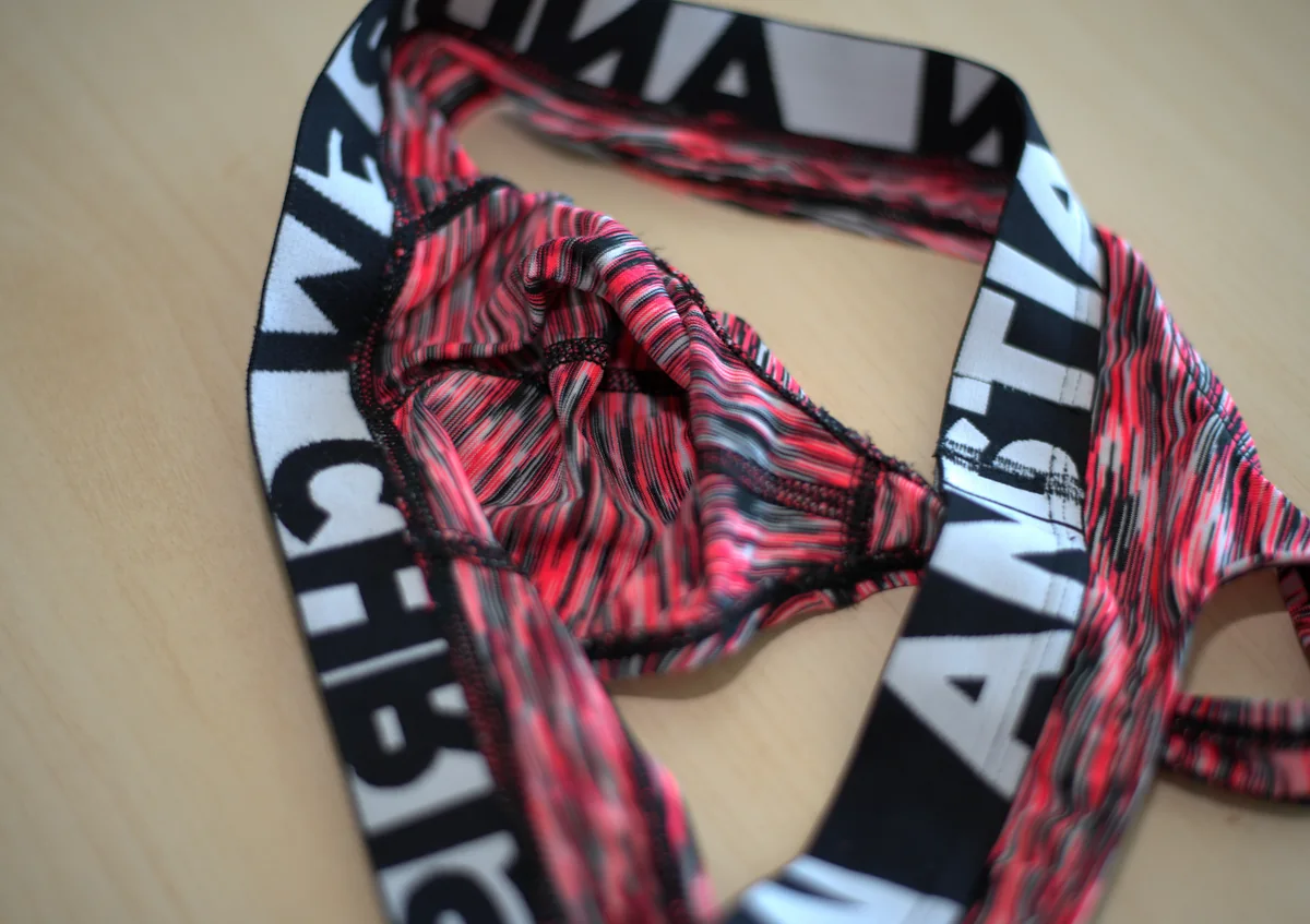 Close-up of the thong's interior pouch, showing the lining, seam structure, elastic edges, and waistband.