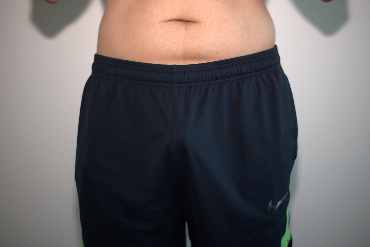 Front view of the tested thong beneath dark gym shorts, framed from the lower abdomen through the upper thighs.
