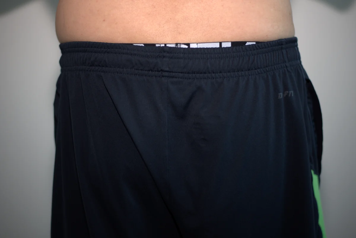 Rear view of the tested thong beneath dark gym shorts, with a narrow section of the underwear waistband visible above the shorts.
