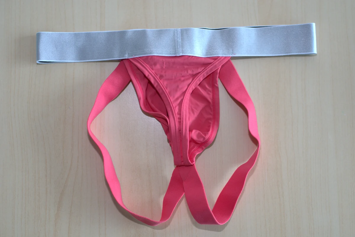Rear flat lay showing the thong panel centered between two separate pink jock straps.