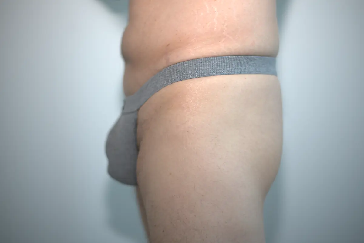 Wide side view of the heather gray AWRY RIBBED Thong, showing its forward pouch shape, higher-rise waistband, and surrounding neutral wall.