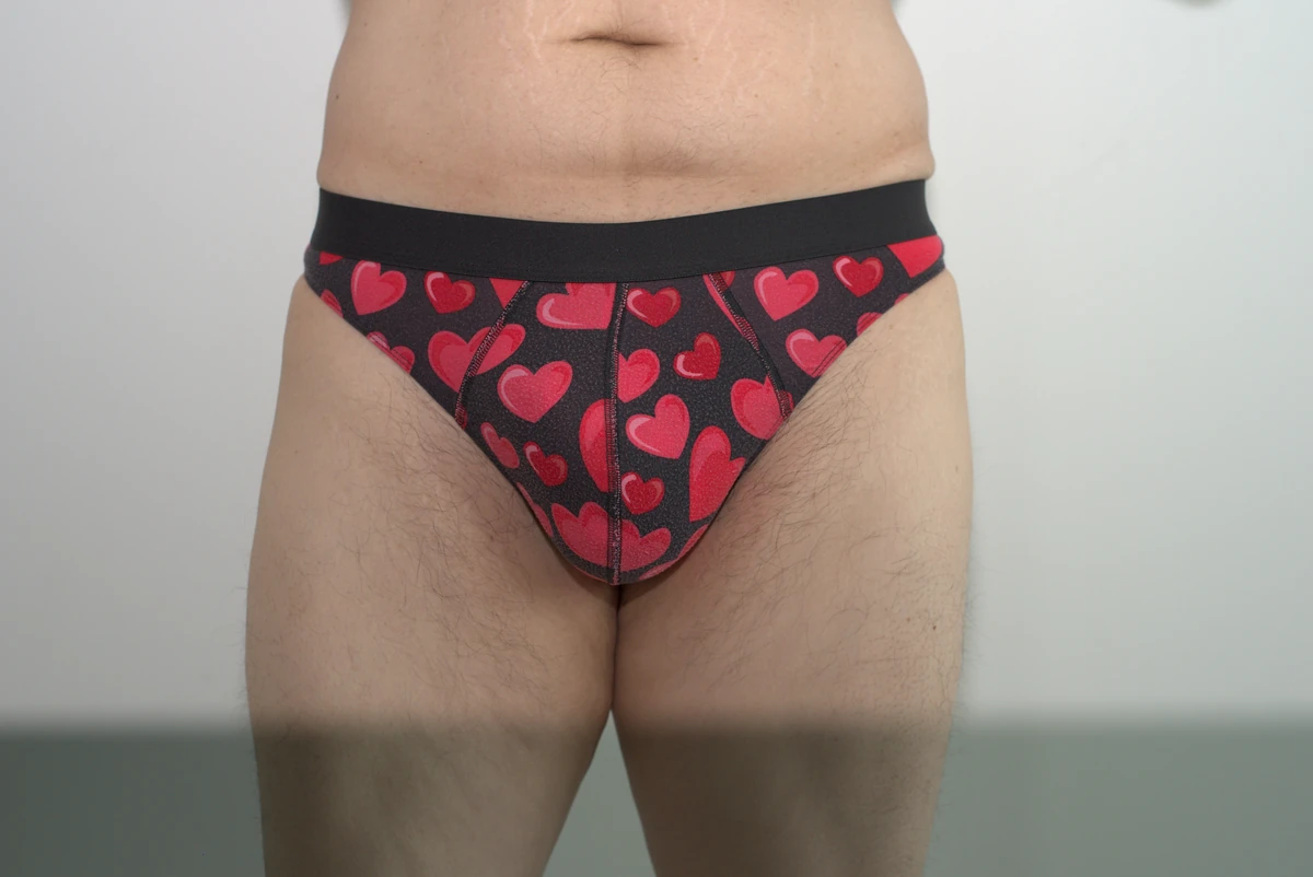 Front view of the MeUndies Pouch Front Thong in the hearts print, size Large, showing the broad front panel and full garment against a neutral wall.