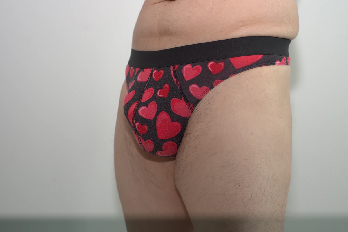 Front three-quarter view of the hearts-print MeUndies Pouch Front Thong in Large, showing its front coverage, side fabric and waistband.