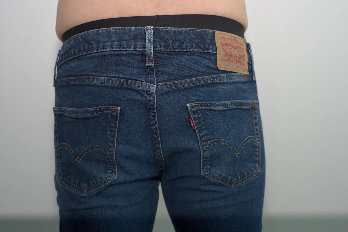 Full rear view of jeans worn over the MeUndies Pouch Front Thong, showing the underwear waistband above the jeans and the surrounding wall.