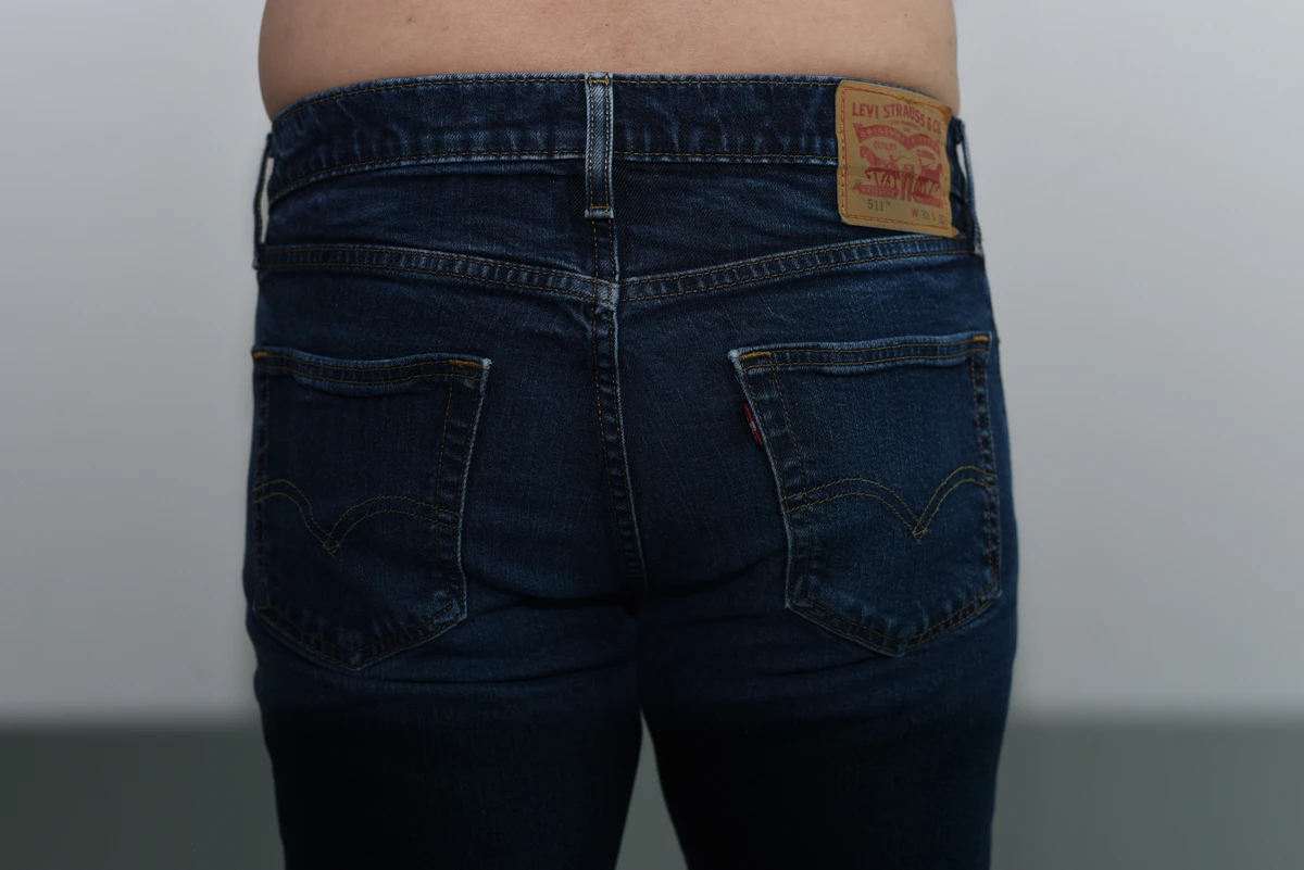 Wider rear view of jeans worn over the SAXX boxer brief, showing the seat and surrounding wall.