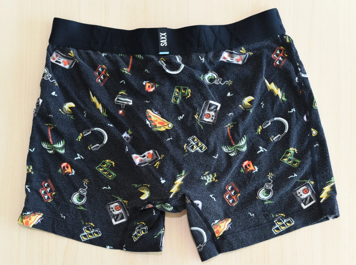Rear flat lay of the black patterned SAXX DropTemp Cooling Cotton Boxer Brief on a light surface.